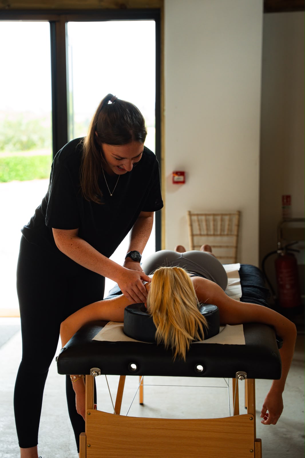 Sports massage therapist treating a client's neck and shoulders in a bright studio